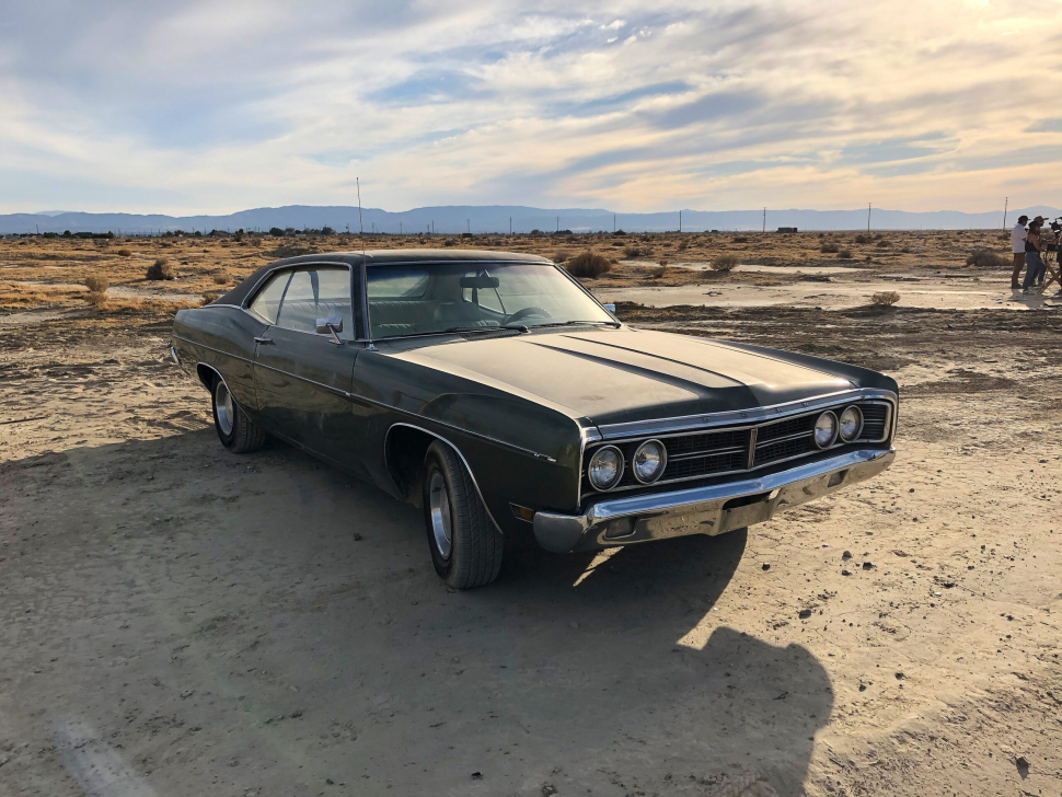A sedan parked at a deserted area under a cloudy sky
